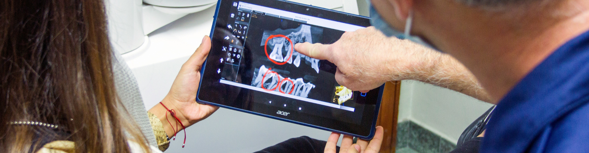 Hand pointing at dental X-ray in two other hands.